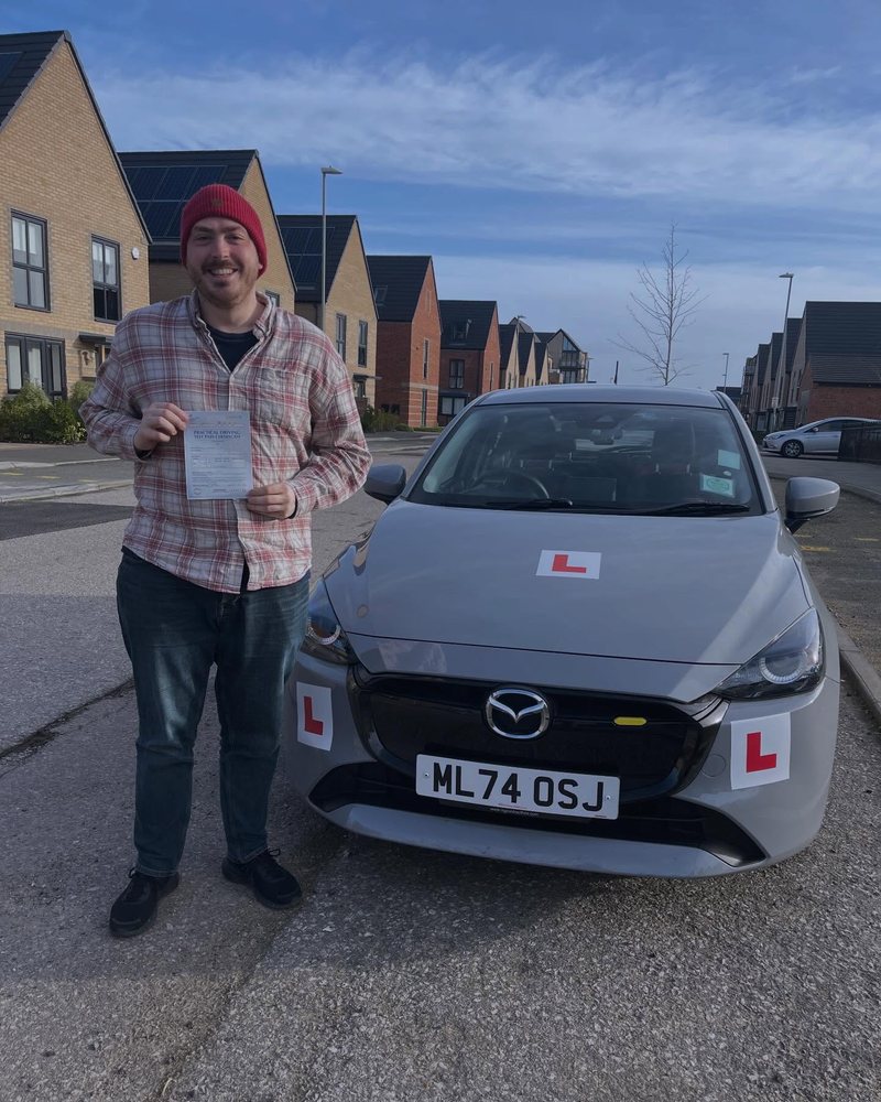 Learner celebrating a driving test pass beside the lesson car in Cambridgeshire